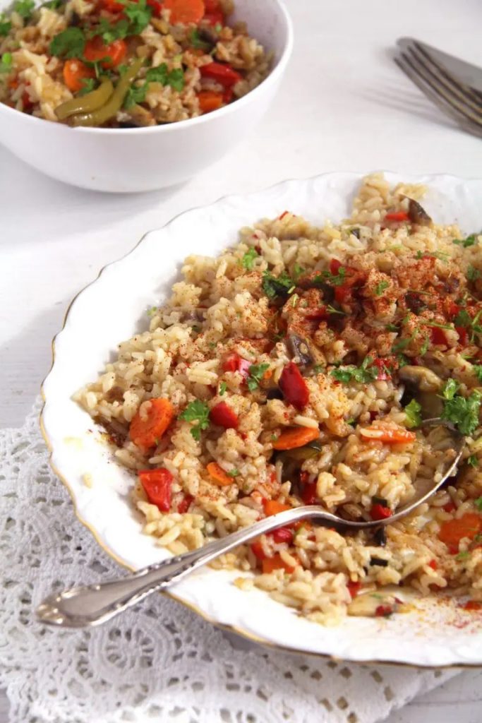 Farfurie si un bol pe masa cu pilaf de orez cu legume și ciuperci