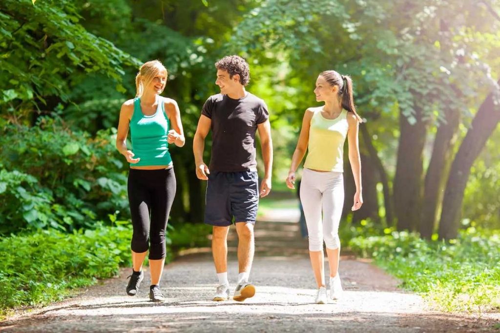 Bărbat și două femei tinere care merg pe jos și socializează în parc