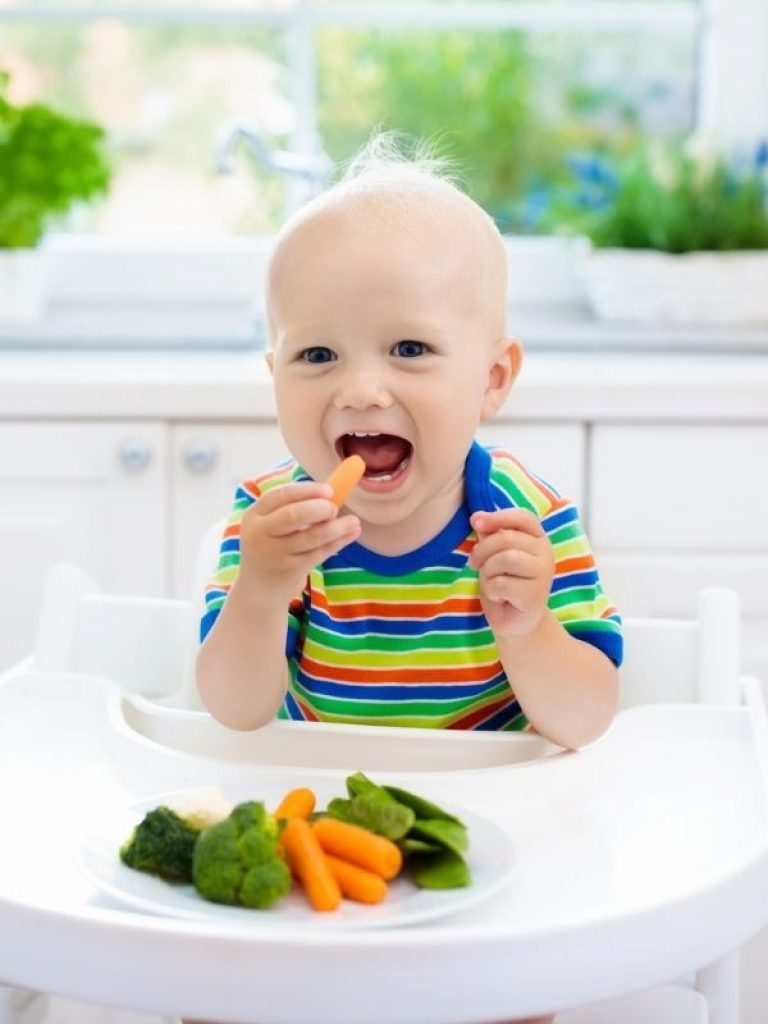 Bebeluș  de peste 6 luni care mănâncă un morcov fiert