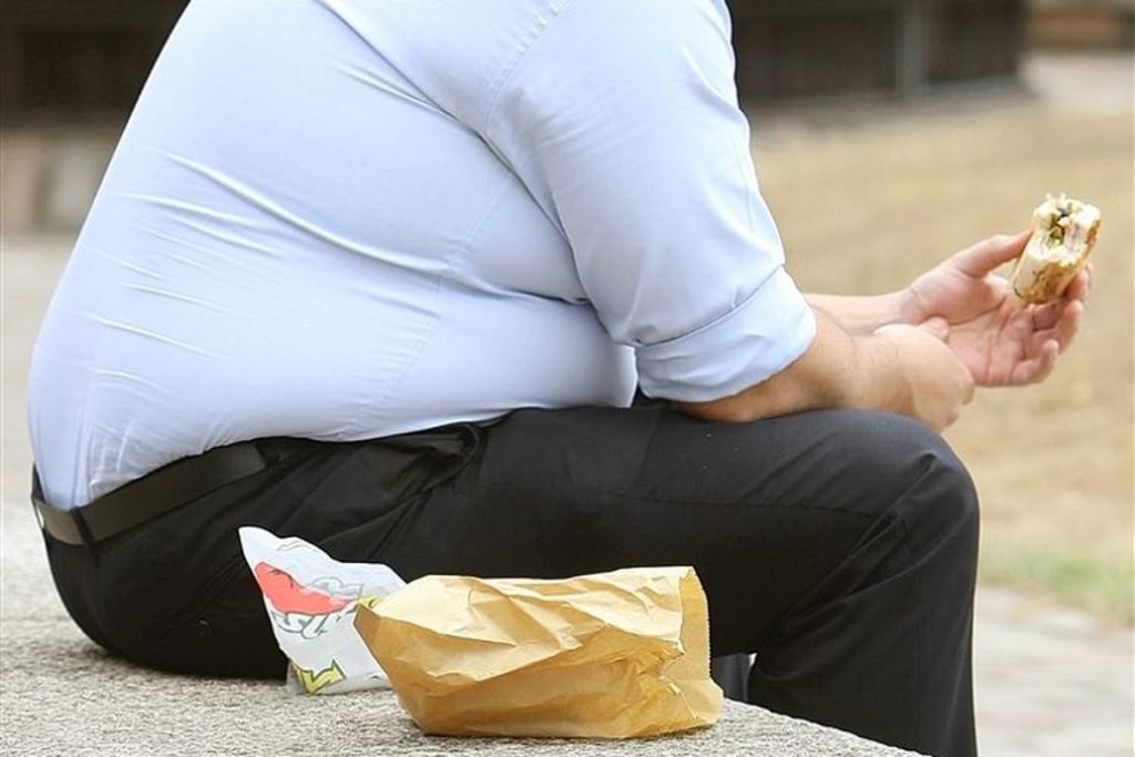 Persoana cu obezitate mâncând alimente nesănătoase