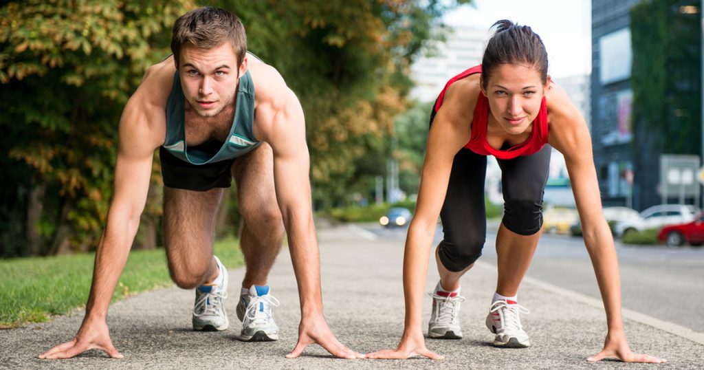 Tânăr cuplu sportiv în poziție de start pregătit să concureze și să alerge