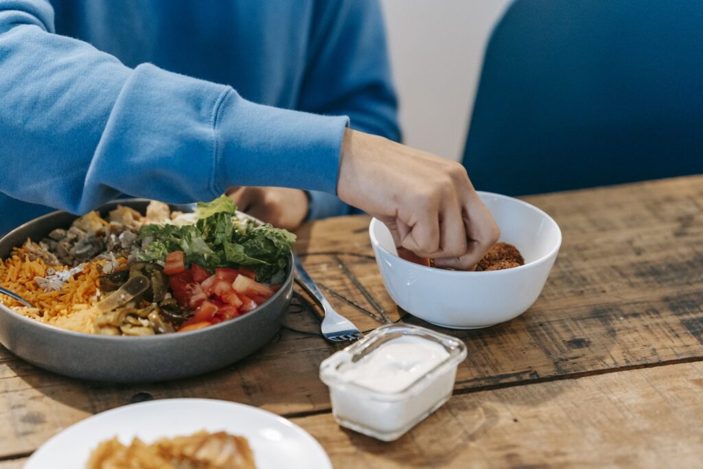 Barbat în bluză de trening albastru având o cină delicioasă la o masă de lemn în bucătărie