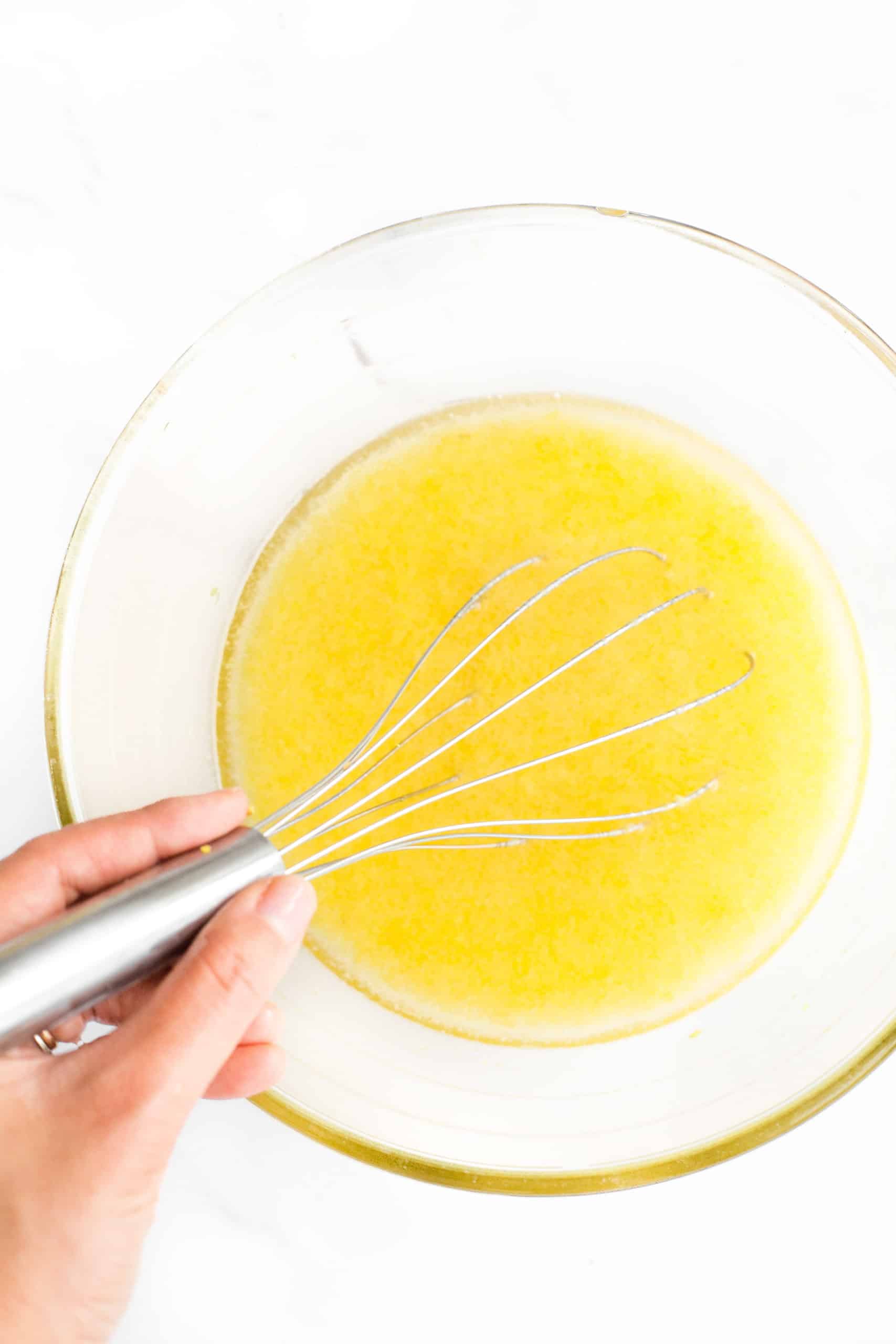 Bateți manual ingredientele pentru lemon curd într-un bol mare de sticlă.