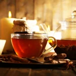 O ceasca cu cu ceai negru aburind, așezată pe o masă de lemn rustică