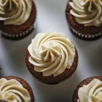 Cupcakes vegane într-o cofetărie modernă. Se observă cum adaugă extract de cafea bio într-o cremă naturală de vanilie, transformând culoarea acesteia într-un maro caramel apetisant. Lumina difuză pune în evidență textura fină a cremei și aspectul profesionist al preparatului.