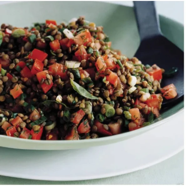 Salată proaspătă și aromată cu linte, bucăți de roșii, mărar și verdeață, servită într-un bol verde elegant, perfectă ca fel de mâncare ușor și sănătos.