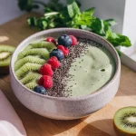 Un smoothie bowl sănătos preparat cu pulbere de baobab, decorat cu felii de kiwi, zmeură, afine și semințe de chia, servit într-un bol ceramic textura, perfect pentru un mic dejun nutritiv.