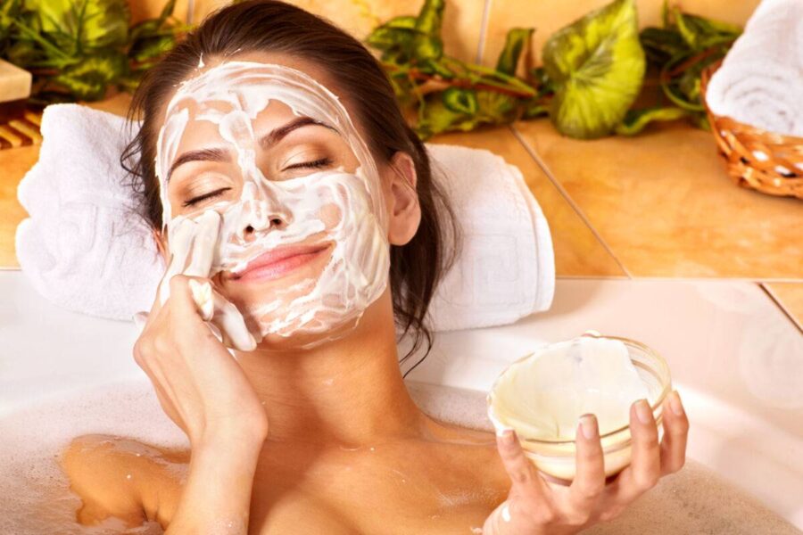 O tânără relaxată aplică o mască facială naturală și hrănitoare pe bază de iaurt în timpul unui tratament spa revitalizant, într-un cadru cu decor verde și luminos.