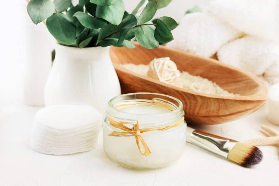 Toner natural cu apă de orez pregătit acasă, prezentat într-un borcan de sticlă decorat cu fundă, alături de discuri demachiante, pensulă cosmetică și frunze proaspete de eucalipt într-o vază albă.