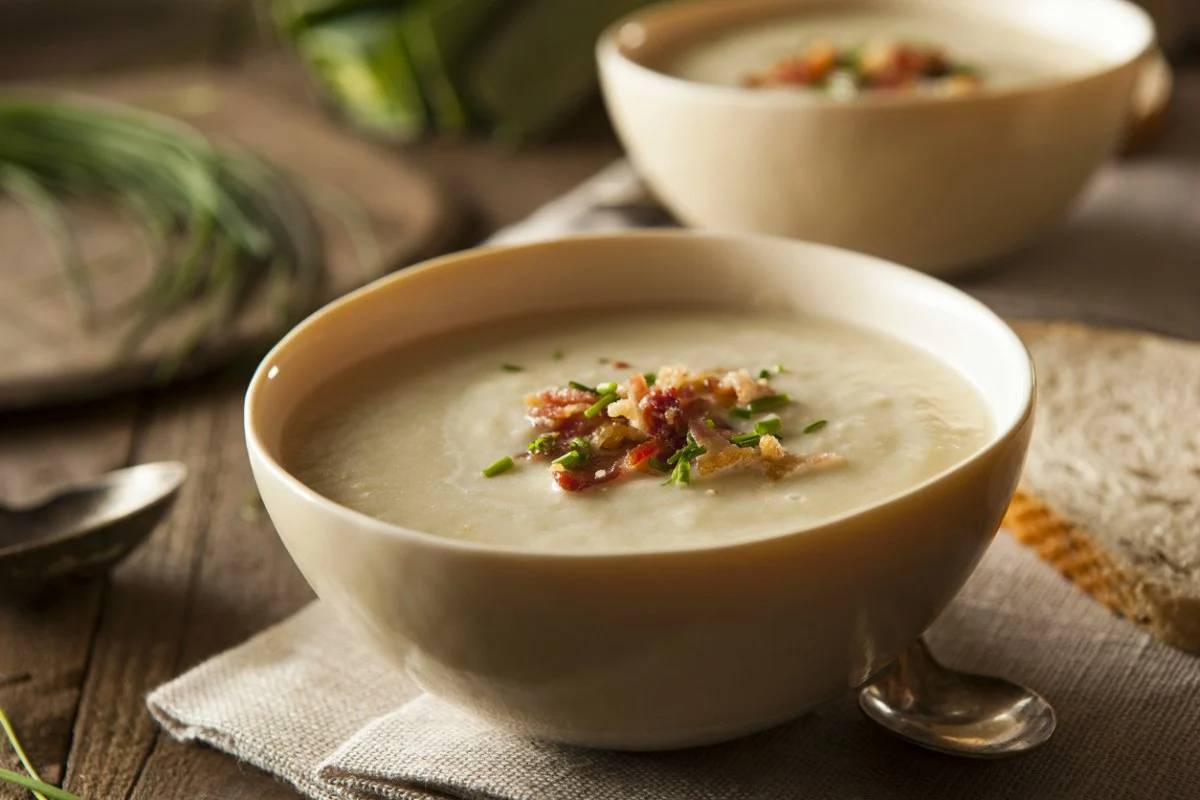 Supă cremă de cartofi - Rețeta simplă și delicioasă Rețetă autentică de supă cremă de cartofi cu textură catifelată, decorată cu bacon crocant și verdeață, servită în stil rustic pentru o experiență culinară caldă și reconfortantă.
